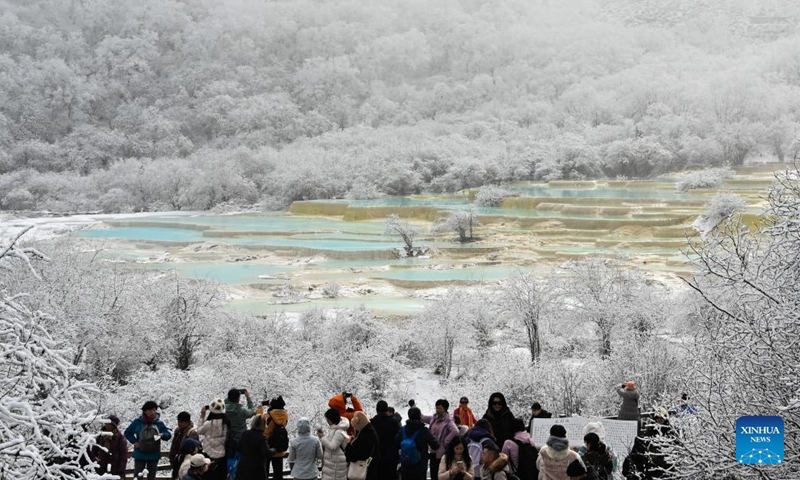 This photo taken on Nov. 18, 2024 shows tourists viewing a colorful pond cluster at Huanglong scenic area after snow in Tibetan-Qiang Autonomous Prefecture, southwest China's Sichuan Province. (Photo: Xinhua)