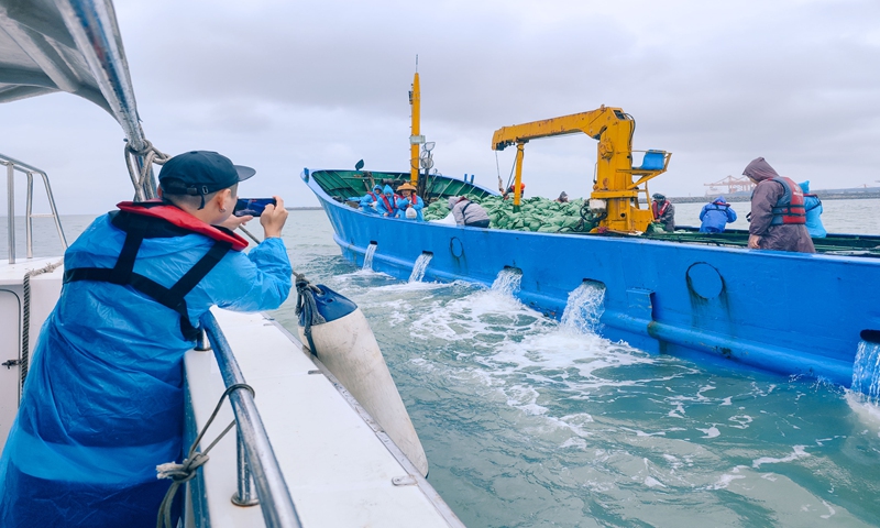 A man takes a picture of a boat crew as they release fish as part of an ecological compensation enrichment and release program in Huizhou, South China' Guangdong Province, on November 20, 2024. Photo: VCG