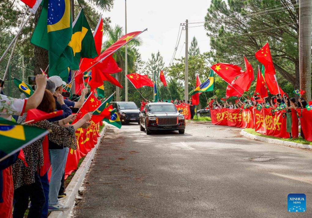 Representatives of overseas Chinese, Chinese institutions and students wave the national flags of China and Brazil on both sides of the road, congratulating Chinese President Xi Jinping on the complete success of his visit, while Xi's motorcade is on its way to the airport in Brasilia, Brazil, Nov. 21, 2024. Xi left Brasilia on Thursday after attending the 19th G20 Leaders' Summit and paying a state visit to Brazil. (Xinhua/Wang Tiancong)