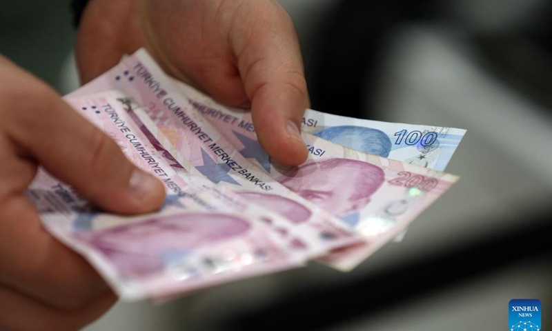 A teller shows banknotes at an exchange office in Ankara, Türkiye, on Nov. 21, 2024. Türkiye's central bank held its key interest rate steady at 50 percent on Thursday for the eighth straight month, in line with market expectations. (Mustafa Kaya/Handout via Xinhua)