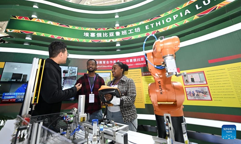 Kalkidan (1st R) introduces an industrial robot training platform to a visitor at the booth of Ethiopian Luban Workshop during the 2024 World Vocational and Technical Education Development Conference in Tianjin, north China, Nov. 22, 2024. (Photo: Xinhua)