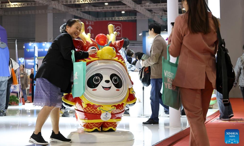 A visitor poses for photos with Bing Dwen Dwen, the mascot for the Beijing 2022 Olympic Winter Games, during the China International Travel Mart 2024 in east China's Shanghai, Nov. 22, 2024.(Photo: Xinhua)