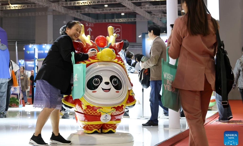 A visitor poses for photos with Bing Dwen Dwen, the mascot for the Beijing 2022 Olympic Winter Games, during the China International Travel Mart 2024 in east China's Shanghai, Nov. 22, 2024. The China International Travel Mart 2024, organized by the Ministry of Culture and Tourism, kicked off Friday in Shanghai, bringing together exhibitors from over 80 countries and regions. The three-day fair has attracted more than 1,000 international exhibitors and nearly 600 travel agencies, along with over 600 offline buyer-seller meetings, according to the organizers. (Xinhua/Fang Zhe)