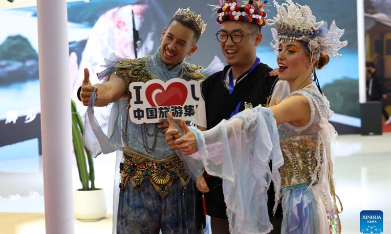 A visitor (C) poses for photos at the booth of China Tourism Group during the China International Travel Mart 2024 in east China's Shanghai, Nov. 22, 2024. (Photo: Xinhua)