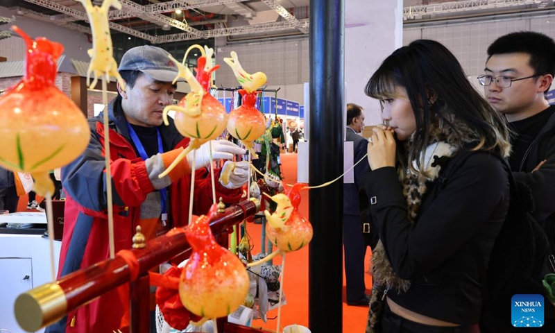 A visitor tries to blow a sugar figure at the booth of east China's Anhui Province during the China International Travel Mart 2024 in east China's Shanghai, Nov. 22, 2024. (Photo: Xinhua)