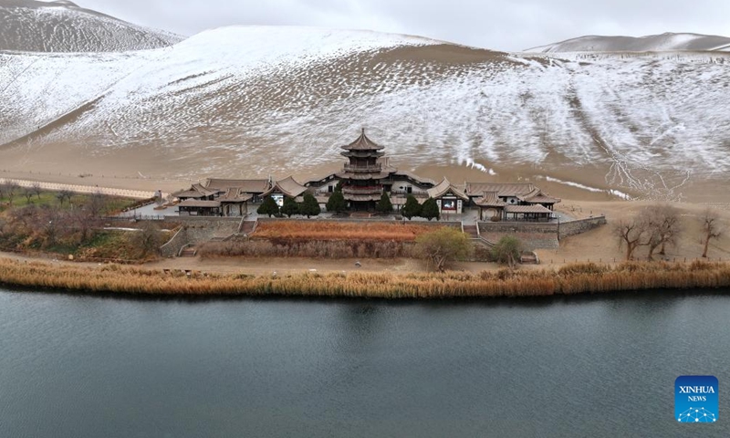 A drone photo taken on Nov. 23, 2024 shows snow scenery of the Mingsha Mountain and Crescent Spring scenic spot in Dunhuang, northwest China's Gansu Province. (Photo by Zhang Xiaoliang/Xinhua)