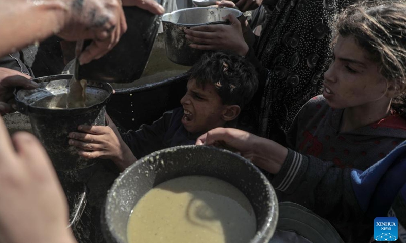 Palestinians receive free food at a food distribution center in the city of Deir al-Balah, central Gaza Strip, on Nov. 23, 2024. (Photo by Rizek Abdeljawad/Xinhua)