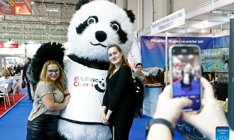 Visitors pose for photos with a giant panda mascot of China's stand at the autumn edition of Romania's Tourism Fair in Bucharest, Romania, Nov. 22, 2024. China's stand attracted visitors at the Romania's Tourism Fair, which is held here from Nov. 21-24, as China has expanded its visa-free policy to nine additional countries including Romania, allowing their citizens to enter for up to 30 days without a visa for business, tourism, and other visits starting Nov. 30, 2024. (Photo by Cristian Cristel/Xinhua)