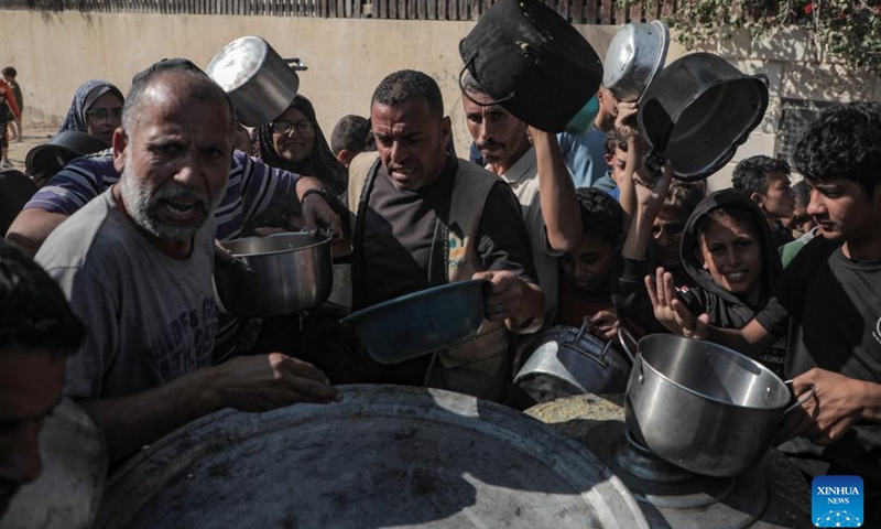 Palestinians receive free food at a food distribution center in the city of Deir al-Balah, central Gaza Strip, on Nov. 23, 2024. (Photo by Rizek Abdeljawad/Xinhua)