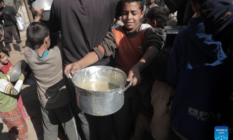 Palestinians receive free food at a food distribution center in the city of Deir al-Balah, central Gaza Strip, on Nov. 23, 2024. (Photo by Rizek Abdeljawad/Xinhua)