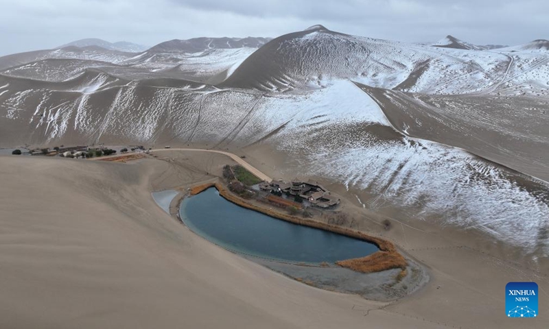 An aerial drone photo taken on Nov. 23, 2024 shows snow scenery of the Mingsha Mountain and Crescent Spring scenic spot in Dunhuang, northwest China's Gansu Province. (Photo by Zhang Xiaoliang/Xinhua)