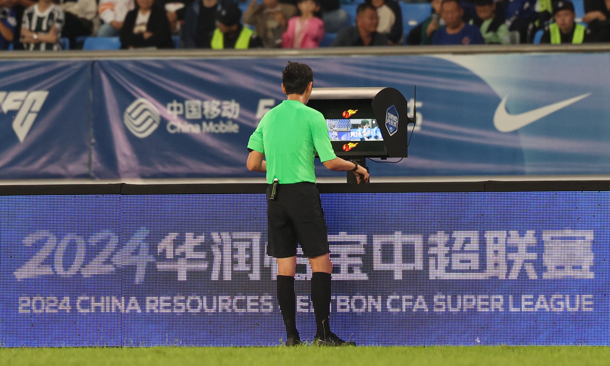 The referee views a pitchside monitor before making a decision during a football match in Cangzhou, North China's Hebei Province. Photo: IC