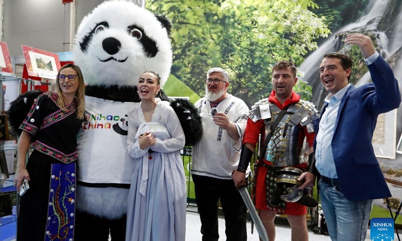 Visitors pose for photos with a giant panda mascot of China's stand at the autumn edition of Romania's Tourism Fair in Bucharest, Romania, Nov. 22, 2024. China's stand attracted visitors at the Romania's Tourism Fair, which is held here from Nov. 21-24, as China has expanded its visa-free policy to nine additional countries including Romania, allowing their citizens to enter for up to 30 days without a visa for business, tourism, and other visits starting Nov. 30, 2024. (Photo by Cristian Cristel/Xinhua)