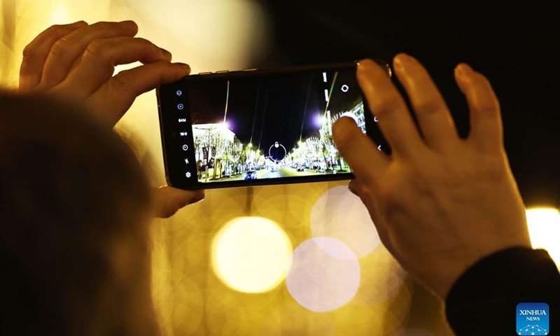 A man takes photos at the Champs-Elysees lit by Christmas holiday lights in Paris, France, Nov. 24, 2024. The annual Christmas season lighting ceremony was held here on Sunday. The lights on the famed avenue will be turned on from 17:00 to midnight everyday and will last until the beginning of January 2024, with the exception of Dec. 24 and 31, when the lights will last all night long. (Xinhua/Gao Jing)