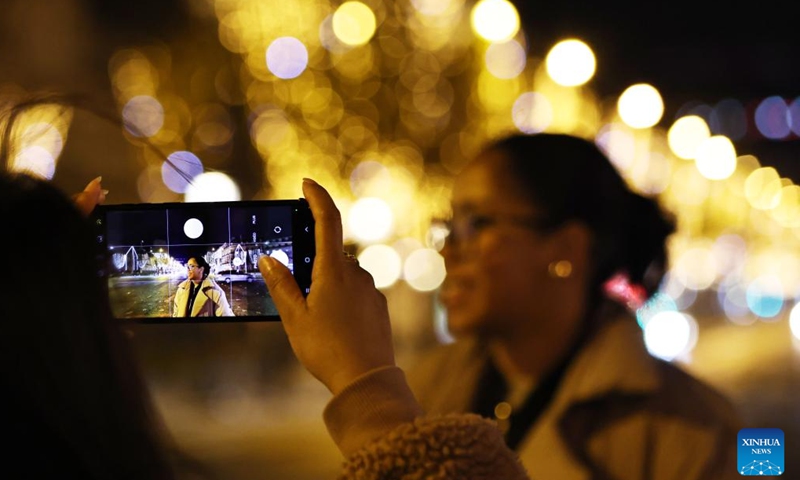 People take photos at the Champs-Elysees lit by Christmas holiday lights in Paris, France, Nov. 24, 2024. The annual Christmas season lighting ceremony was held here on Sunday. The lights on the famed avenue will be turned on from 17:00 to midnight everyday and will last until the beginning of January 2024, with the exception of Dec. 24 and 31, when the lights will last all night long. (Xinhua/Gao Jing)