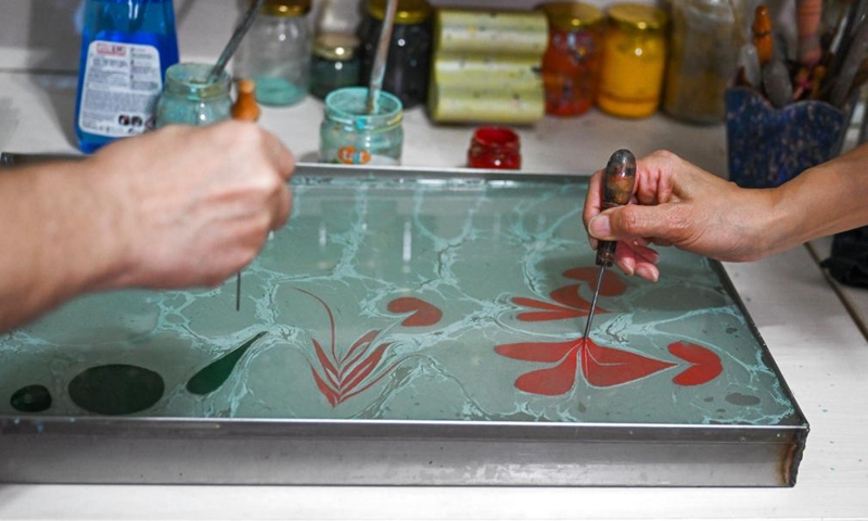 Li Xintong (R) and her teacher Erol Caglar work on a piece of Ebru art in Istanbul, Türkiye, Nov. 1, 2024. Ebru, or the Turkish art of paper marbling, is a traditional painting art. To create an Ebru, the artist will have to paint on water and then transfer this painting onto paper. In 2014, Ebru was officially listed as a UNESCO World Intangible Culture Heritage. (Photo: Xinhua)