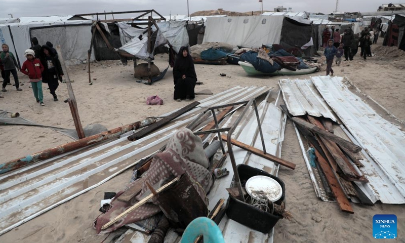 A woman sits by a tent damaged in heavy rain in the Mawasi area of Khan Younis, southern Gaza Strip, on Nov. 25, 2024. UN humanitarians said on Monday they and their partners have been evaluating flood damage in a response to multiple sites for displaced Gazans hit by heavy weekend rainfall. (Photo: Xinhua)