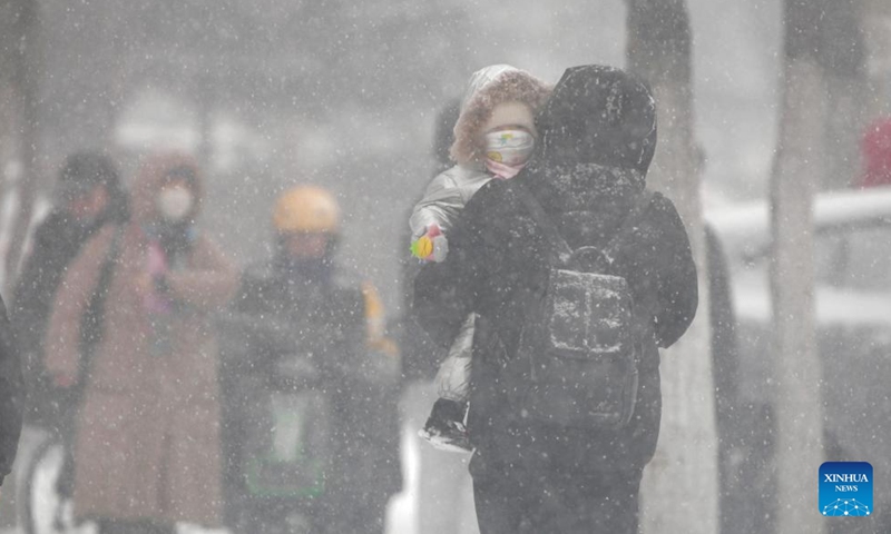 A pedestrian carries a child on a snowy day in Qiqihar, northeast China's Heilongjiang Province, Nov. 25, 2024. (Photo: Xinhua)