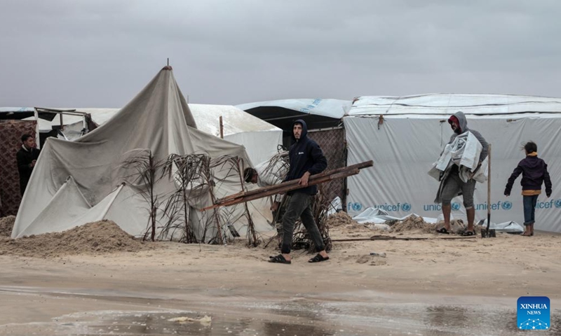 People collect items near a tent damaged in heavy rain in the Mawasi area of Khan Younis, southern Gaza Strip, on Nov. 25, 2024. UN humanitarians said on Monday they and their partners have been evaluating flood damage in a response to multiple sites for displaced Gazans hit by heavy weekend rainfall. (Photo: Xinhua)