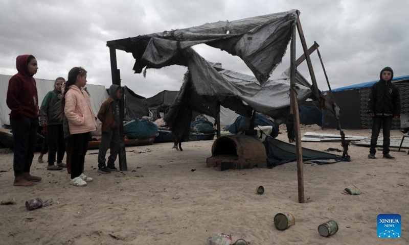 Children stand by a tent damaged in heavy rain in the Mawasi area of Khan Younis, southern Gaza Strip, on Nov. 25, 2024. UN humanitarians said on Monday they and their partners have been evaluating flood damage in a response to multiple sites for displaced Gazans hit by heavy weekend rainfall. (Photo: Xinhua)