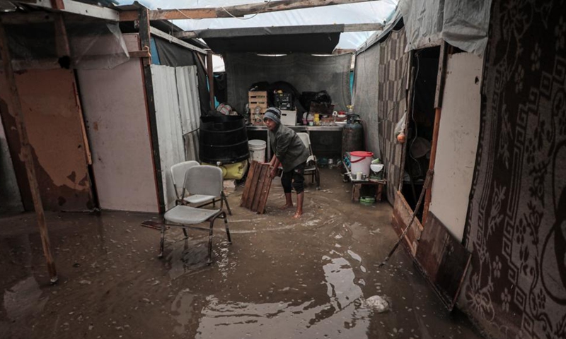 A boy is seen inside a flooded tent after heavy rain in the Mawasi area of Khan Younis, southern Gaza Strip, on Nov. 25, 2024. UN humanitarians said on Monday they and their partners have been evaluating flood damage in a response to multiple sites for displaced Gazans hit by heavy weekend rainfall. (Photo: Xinhua)