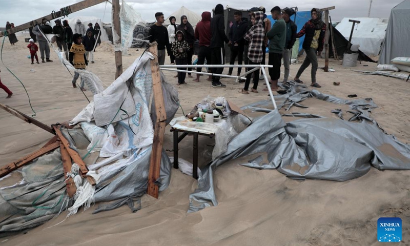 People stand by a tent damaged in heavy rain in the Mawasi area of Khan Younis, southern Gaza Strip, on Nov. 25, 2024. UN humanitarians said on Monday they and their partners have been evaluating flood damage in a response to multiple sites for displaced Gazans hit by heavy weekend rainfall. (Photo: Xinhua)