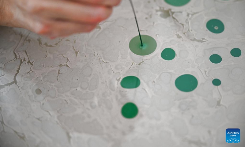 Li Xintong tests the paints for an Ebru creation in Istanbul, Türkiye, Nov. 5, 2024. Ebru, or the Turkish art of paper marbling, is a traditional painting art. To create an Ebru, the artist will have to paint on water and then transfer this painting onto paper. In 2014, Ebru was officially listed as a UNESCO World Intangible Culture Heritage. (Photo: Xinhua)