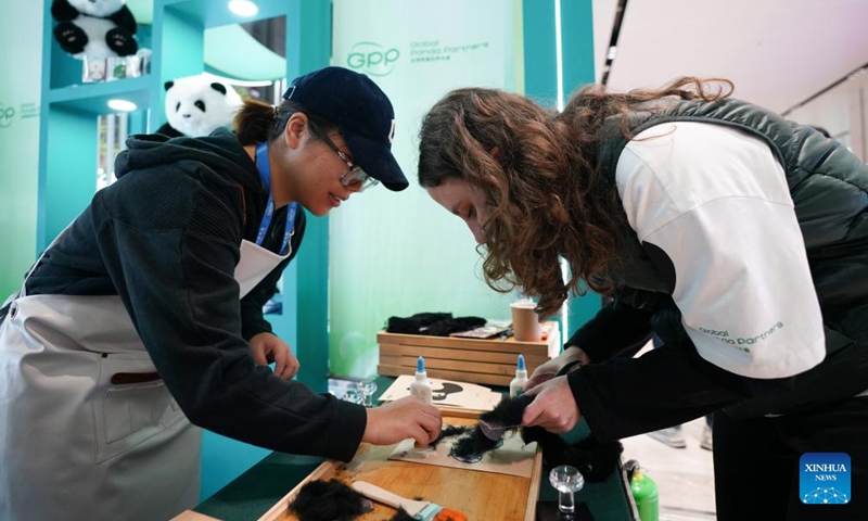 A guest tries to make a giant panda plush toy during the Global Panda Partners 2024 conference in Chengdu, southwest China's Sichuan Province, Nov. 26, 2024. The event opened here on Tuesday with the theme Harmonious Coexistence Between Man and Nature. (Photo: Xinhua)