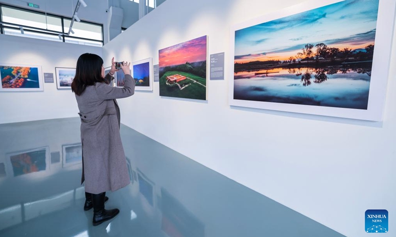 A visitor takes photos at a photography exhibition themed on China's world heritage in Hangzhou, east China's Zhejiang Province, Nov. 25, 2024. The exhibition held here on Monday presents China's 59 sites that have been inscribed on the UNESCO World Heritage List. (Photo: Xinhua)