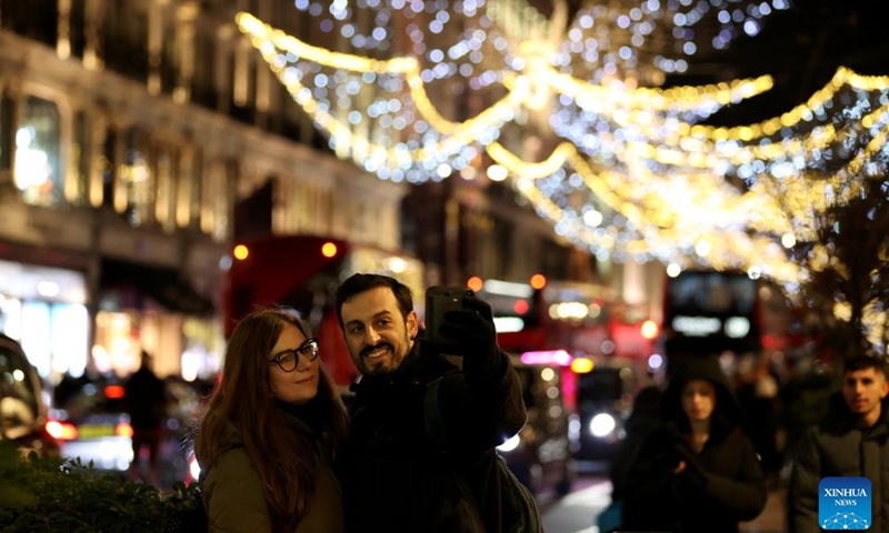 People take selfies on Regent Street decorated with lights in central London, Britain, on Nov. 27, 2024. (Xinhua/Li Ying)