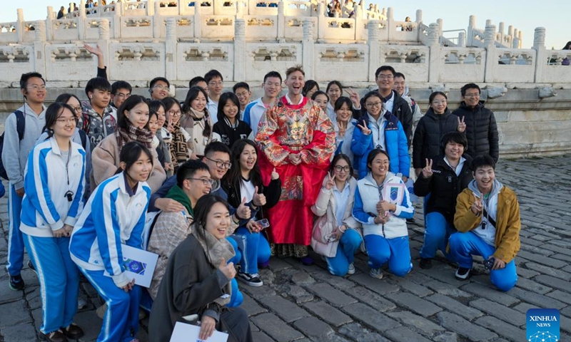 Evan Kail poses for a group photo with students at Tiantan (Temple of Heaven) Park in Beijing, capital of China, Nov. 21, 2024. (Xinhua/Ju Huanzong)