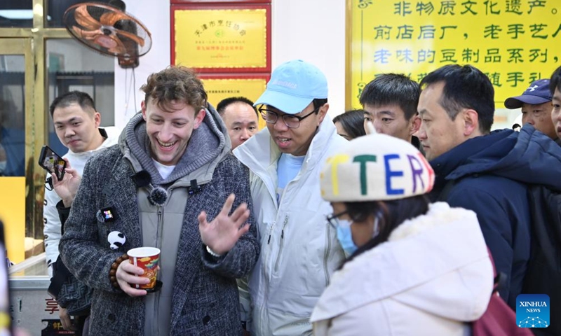 Evan Kail (L, front), a pawnshop manager from the United States, visits a cultural street in north China's Tianjin Municipality, Nov. 28, 2024.