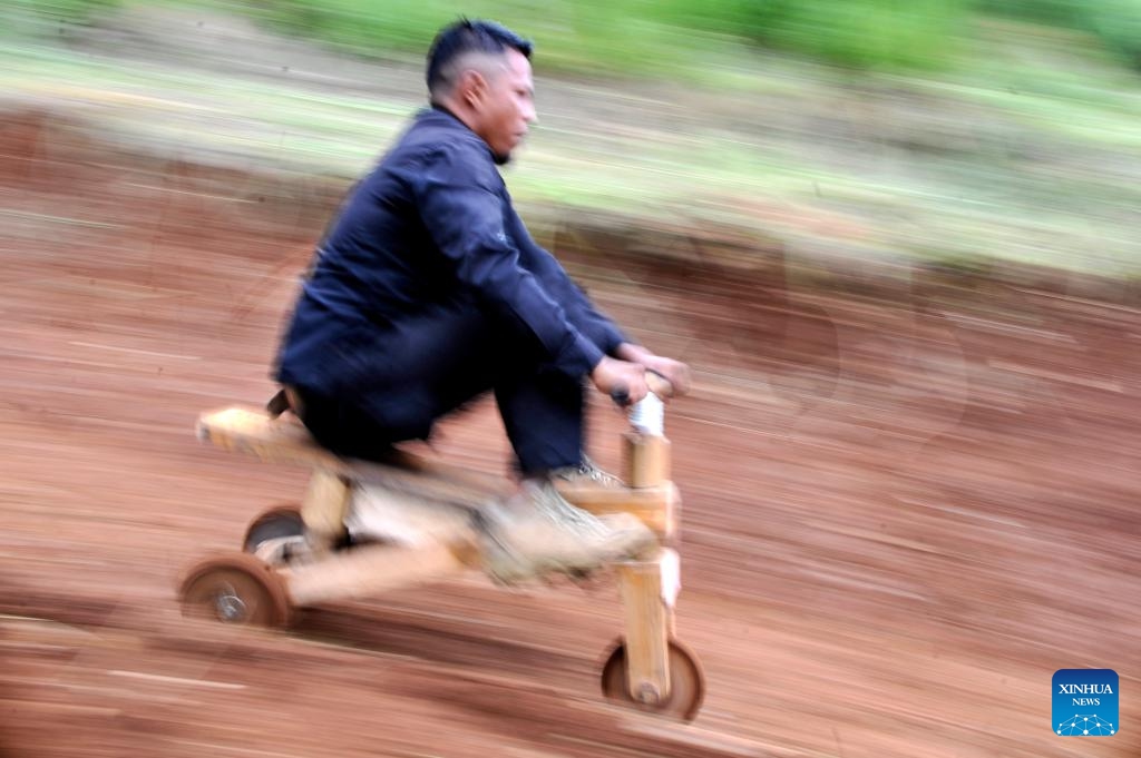 A participant rides a traditional wooden cart, known locally as kadaplak, downhill at Cisurupan in Bandung, West Java Province, Indonesia, Nov. 28, 2024. (Photo by Septianjar Muharam/Xinhua)