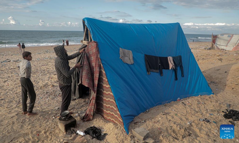 Odai Olaiwa (R) fixes a tent on the beach of Deir al-Balah in the central Gaza Strip, on Nov. 28, 2024. (Photo: Xinhua)