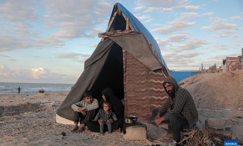 Odai Olaiwa (1st R) and his family are pictured beside a tent on the seaside in the city of Deir al-Balah in central Gaza Strip, Nov. 28, 2024. (Photo: Xinhua)