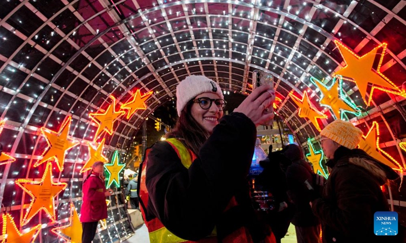 A woman takes photos of the Christmas lights during the Lights of Hope lighting ceremony in Vancouver, British Columbia, Canada, Nov. 27, 2024. Lights of Hope is one of Vancouver's largest annual Christmas fundraiser, showcasing over 200,000 colourful lights illuminating St. Paul's Hospital. (Photo by Liang Sen/Xinhua)