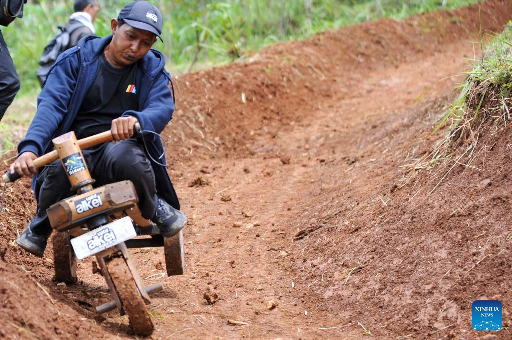 A participant rides a traditional wooden cart, known locally as kadaplak, downhill at Cisurupan in Bandung, West Java Province, Indonesia, Nov. 28, 2024. (Photo by Septianjar Muharam/Xinhua)