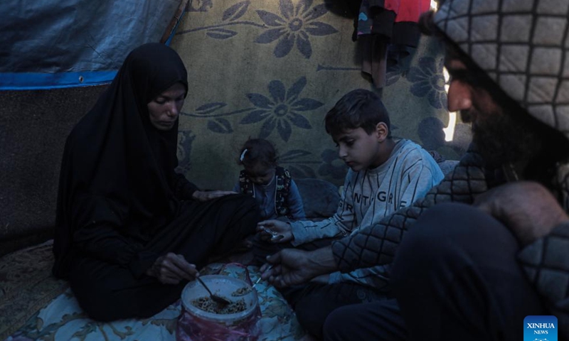 Odai Olaiwa (1st R) and his family have a meal inside a tent on the seaside in the city of Deir al-Balah in central Gaza Strip, Nov. 28, 2024. (Photo: Xinhua)