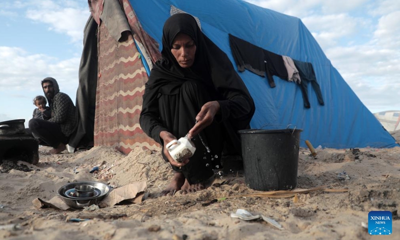 Odai Olaiwa's wife washes utensils on the seaside in the city of Deir al-Balah in central Gaza Strip, Nov. 28, 2024. (Photo: Xinhua)