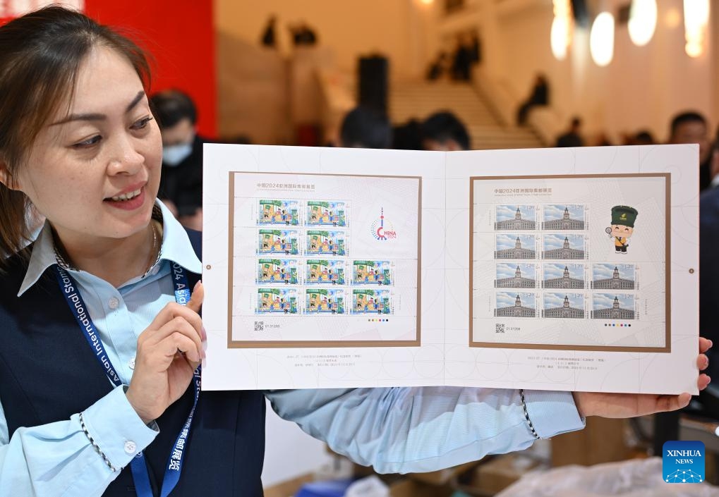 A staff member shows commemorative stamps issued by China Post for China 2024 Asian International Stamp Exhibition at Shanghai Exhibition Center in east China's Shanghai on Nov. 29, 2024. The exhibition opened on Friday and will last for 5 days. (Xinhua/Li He)