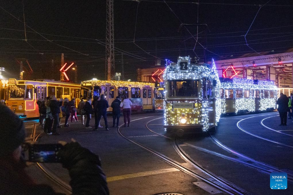 People take photos of the Christmas light-decorated trams in Budapest, Hungary on Dec. 2, 2024. (Photo: Xinhua)