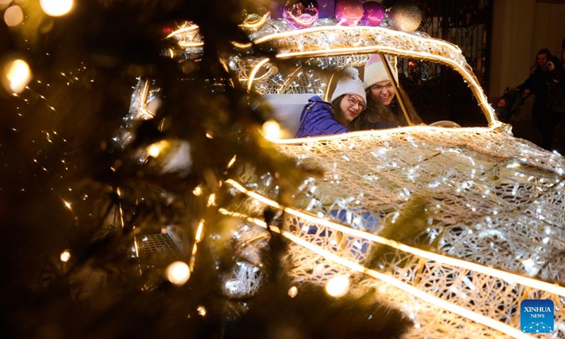 People are seen with a light decoration in the shape of car in Warsaw, Poland, on Dec. 5, 2024. Photo: Xinhua