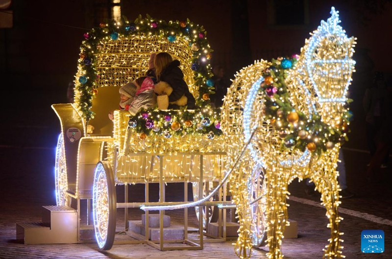 People are seen with a light decoration in the shape of carriage in Warsaw, Poland, on Dec. 5, 2024. Photo: Xinhua