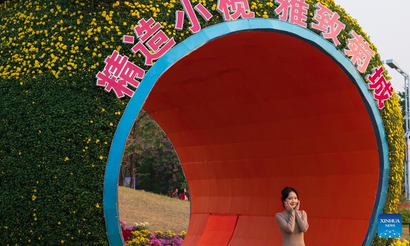 A visitor poses for photos at the 2024 Xiaolan chrysanthemum exhibition in Xiaolan Town of Zhongshan City, south China's Guangdong Province, Dec. 5, 2024. The 2024 Xiaolan chrysanthemum exhibition is held here from Nov. 29 to Dec. 18. This year's exhibition will showcase over 1,000 varieties of chrysanthemums. (Photo: Xinhua)