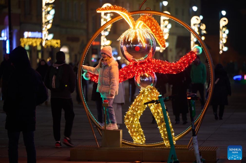 A girl poses for a photo beside a light decoration in Warsaw, Poland, on Dec. 5, 2024. Photo: Xinhua