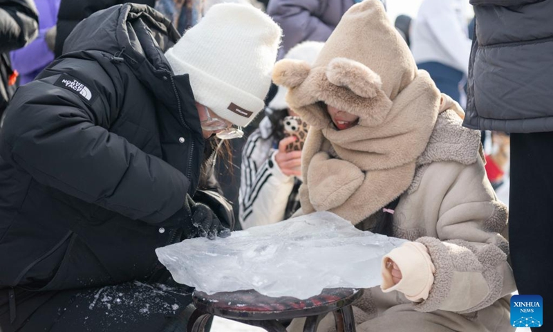 Tourists try to make an ice sculpture during an ice collecting festival in Harbin, northeast China's Heilongjiang Province, Dec. 7, 2024. Marking the beginning of Harbin's ice collecting season, the fifth ice collecting festival kicked off here by the Songhua River on Saturday, attracting lots of people with ice collecting ceremony and performances. Photo: Xinhua