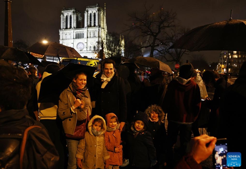 People pose for photos outside the restored Notre-Dame de Paris cathedral in the rain in Paris, France, Dec. 7, 2024. Five years after being devastated by a fire, the restored Notre-Dame de Paris cathedral officially reopened on Saturday with a grand inauguration ceremony attended by world leaders, believers, and non-believers alike. Photo: Xinhua