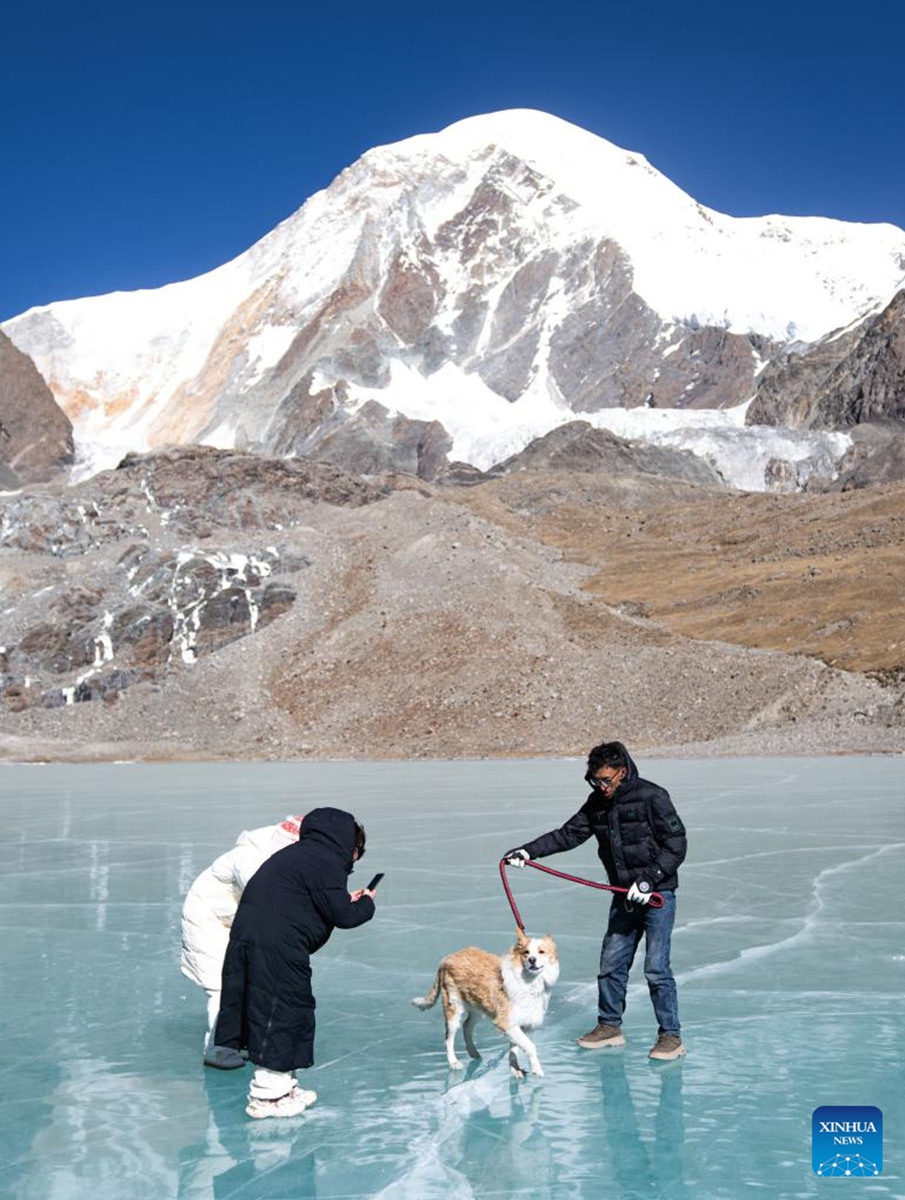 Tourists enjoy themselves on an icy lake in front of the Mount Qungmknag in Nyemo County of Lhasa, southwest China's Xizang Autonomous Region, Dec. 7, 2024. Photo: Xinhua