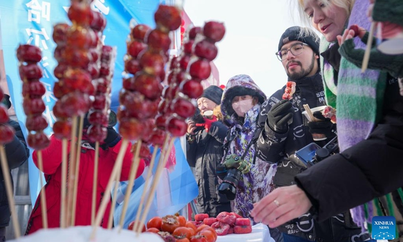 Foreign tourists taste snacks during an ice collecting festival in Harbin, northeast China's Heilongjiang Province, Dec. 7, 2024. Marking the beginning of Harbin's ice collecting season, the fifth ice collecting festival kicked off here by the Songhua River on Saturday, attracting lots of people with ice collecting ceremony and performances. Photo: Xinhua