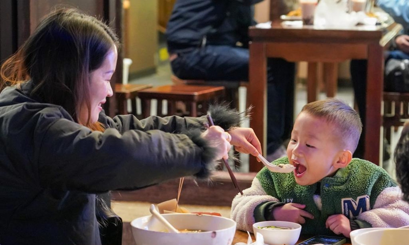 Tourists have rice noodles at a restaurant on a street at night in Kunming City, southwest China's Yunnan Province, Dec. 6, 2024. In recent years, Kunming has stepped up its efforts to enrich citizen's life by developing night fair compounds. Photo: Xinhua